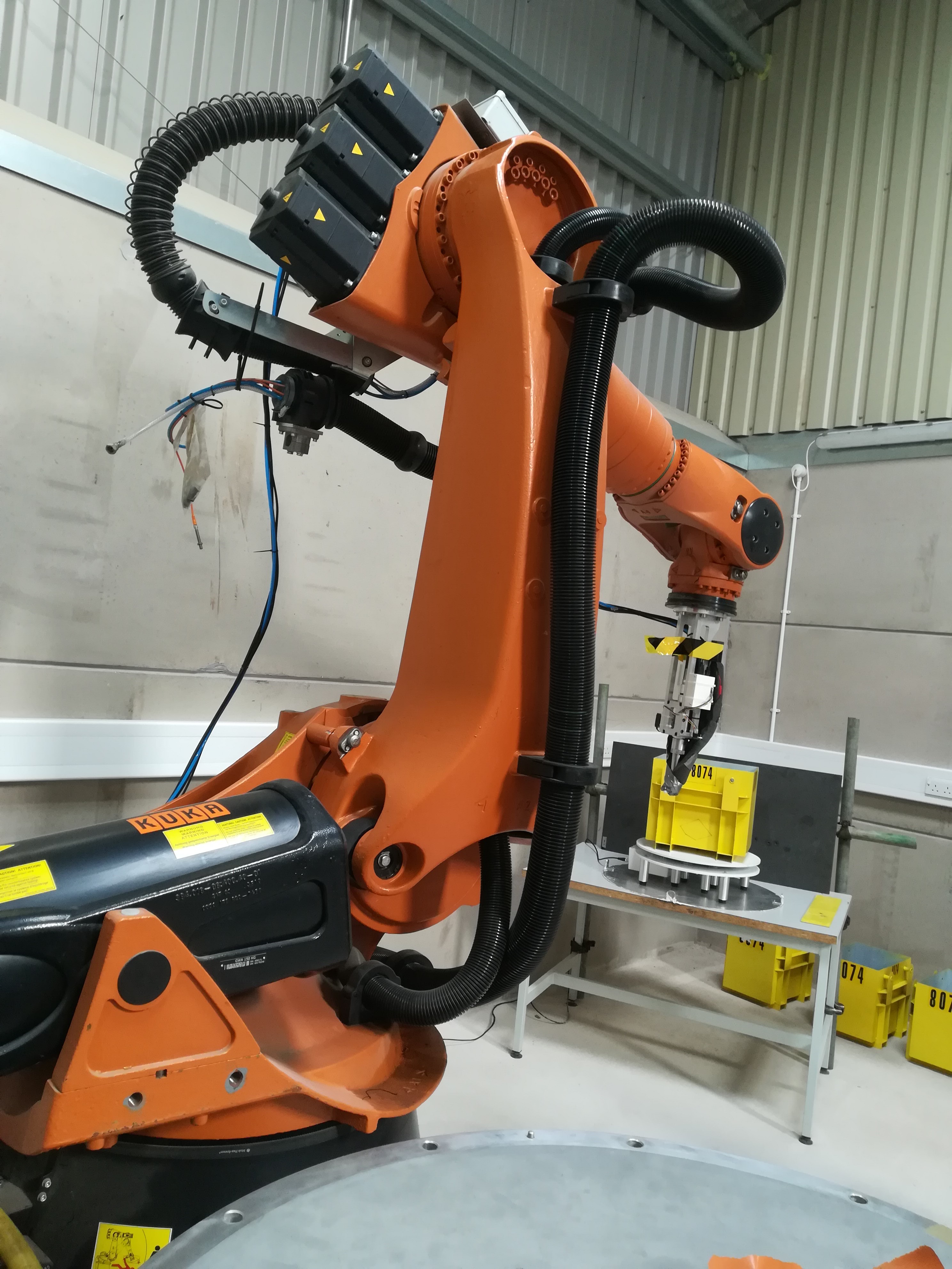 A KUKA robot arm in front of a waste container